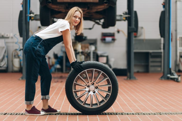 Mechanik kontroluje a vyvažuje kolesá auta počas jarnej výmeny pneumatík.